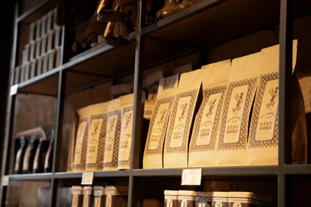 Artisan coffee bags neatly arranged on rustic shelves in a cozy shop setting.