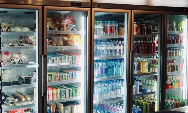 Refrigerator display with various beverages and snacks in a store environment.