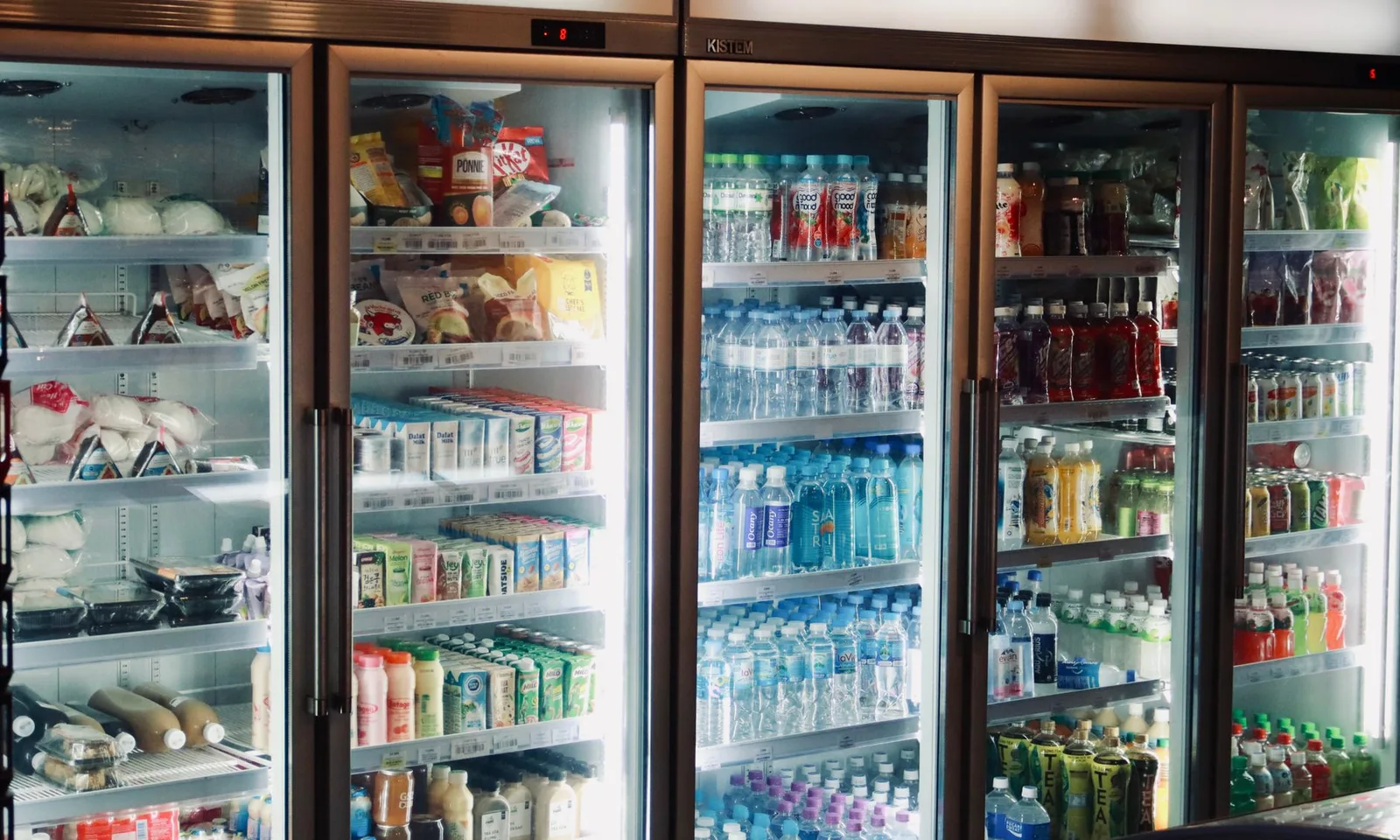 Refrigerator display with various beverages and snacks in a store environment.