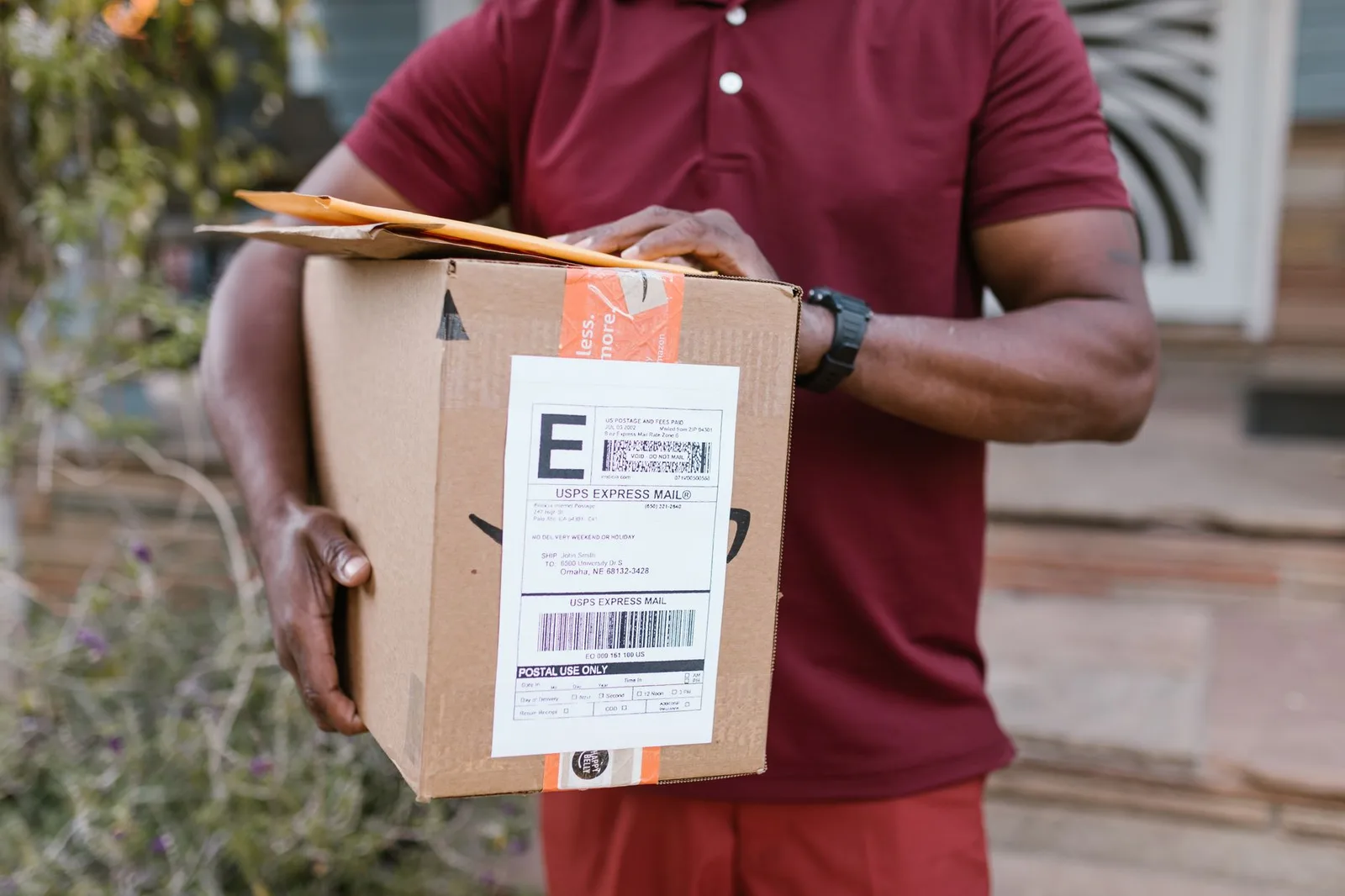 Close-up of a courier delivering a parcel with USPS express mail label outdoors.
